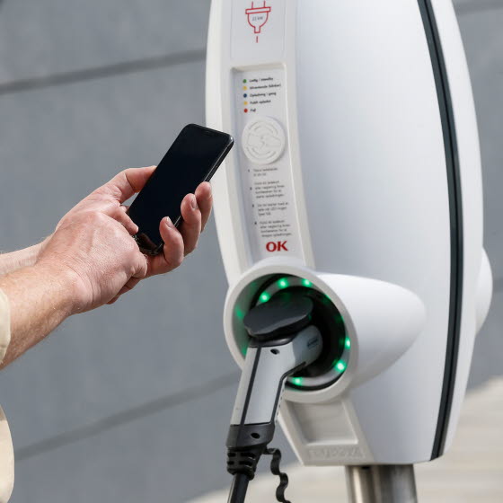 Mand med mobiltelefon ved OK Ladestander