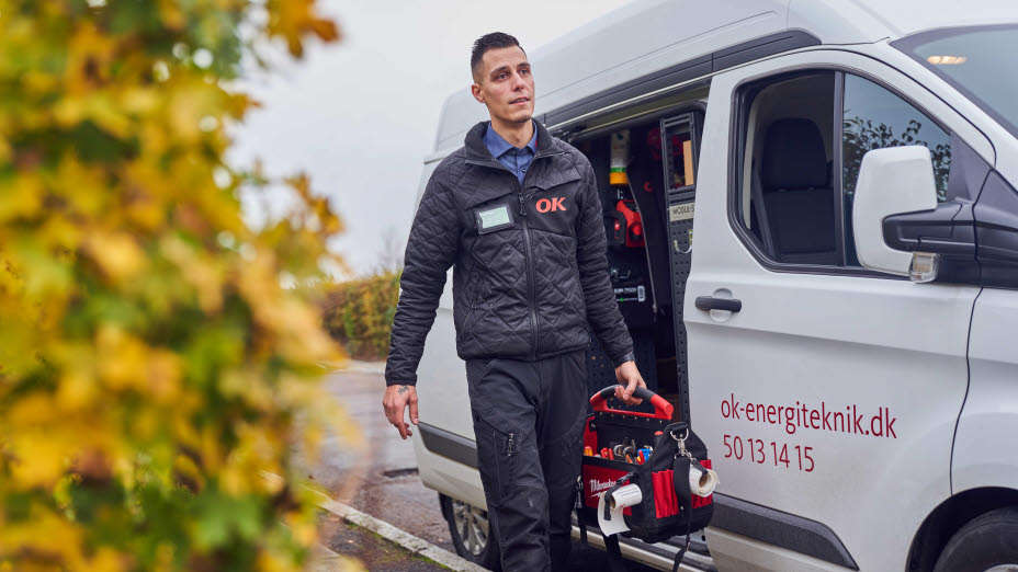 Servicetekniker går med værktøj fra sin bil